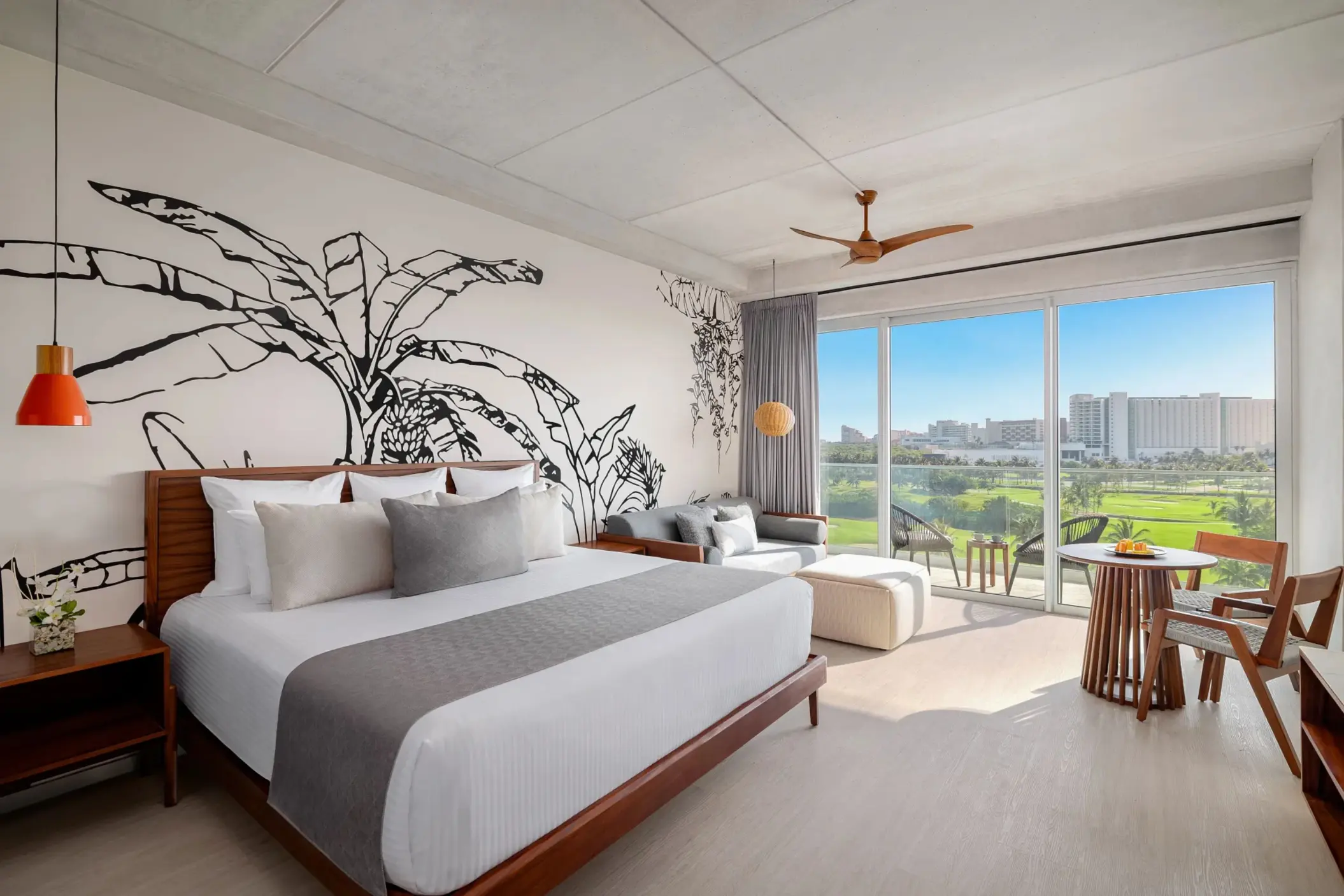 Junior suite with king bed, sleek wood furnishings, and balcony overlooking golf course and greenery.
