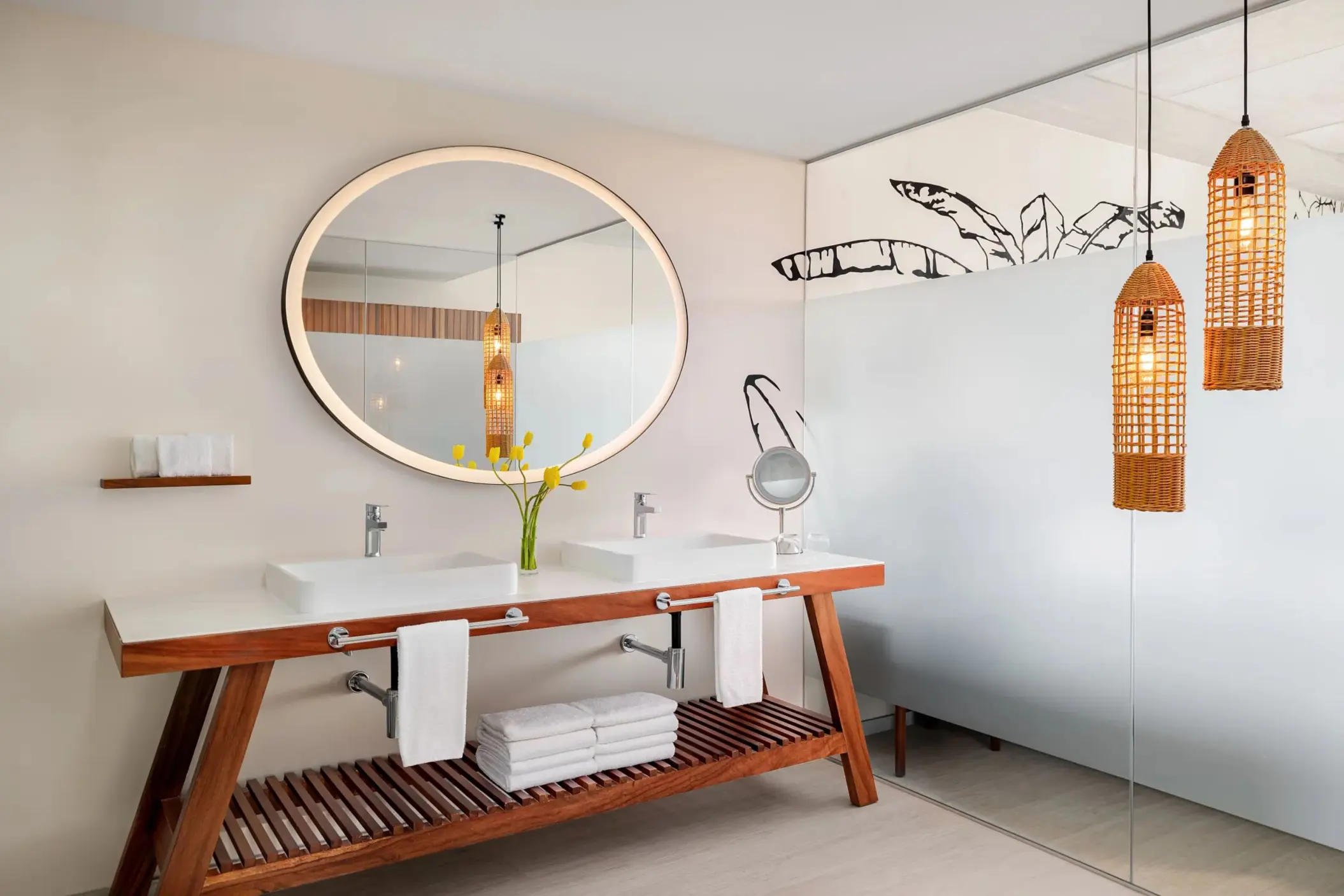 Modern junior suite bathroom with double vanities, round mirrors, and a freestanding soaking tub.