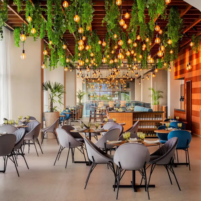 Chic indoor restaurant with hanging greenery and warm pendant lights, modern seating, and stylish wood accents.