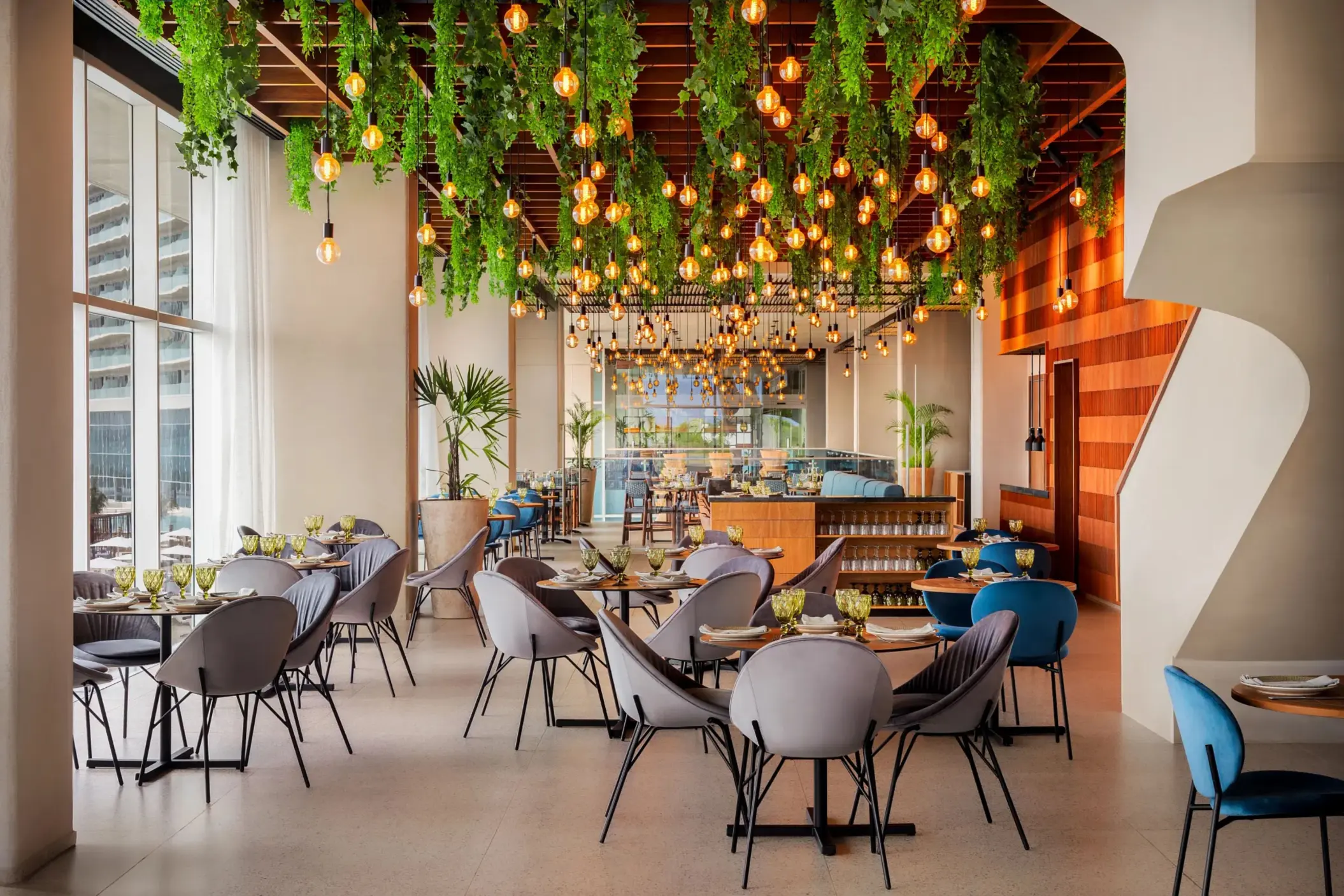 Chic indoor restaurant with hanging greenery and warm pendant lights, modern seating, and stylish wood accents.