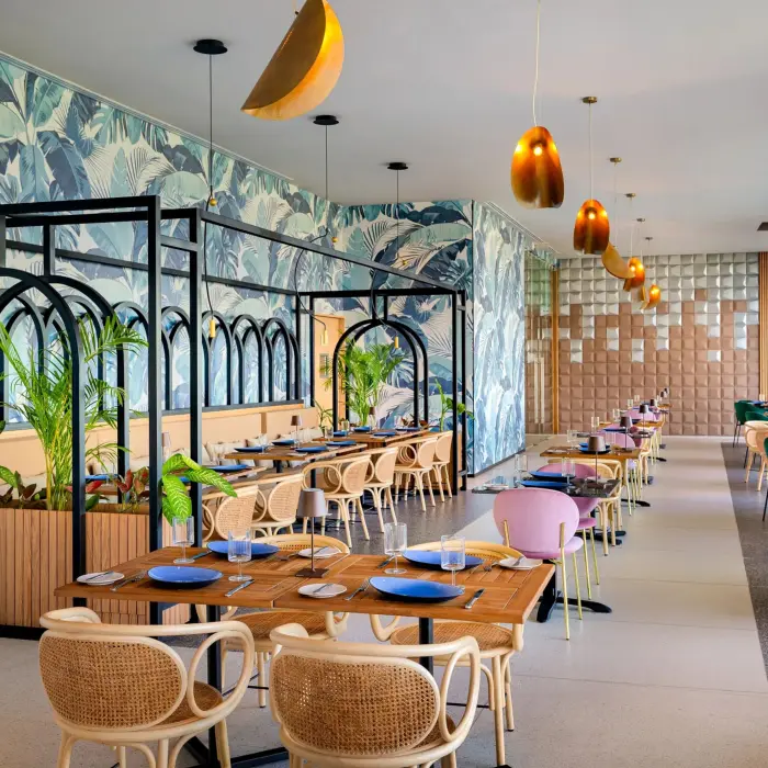 Vibrant dining space with botanical wallpaper, pastel chairs, and black arch dividers for a stylish ambiance.