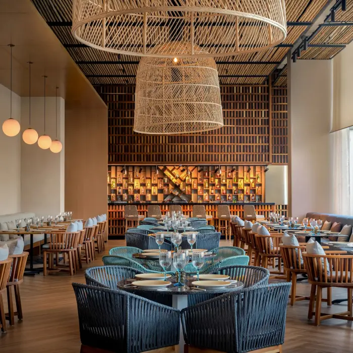 Warm Mediterranean-style restaurant with woven lights, wooden seating, and a cozy, modern aesthetic.