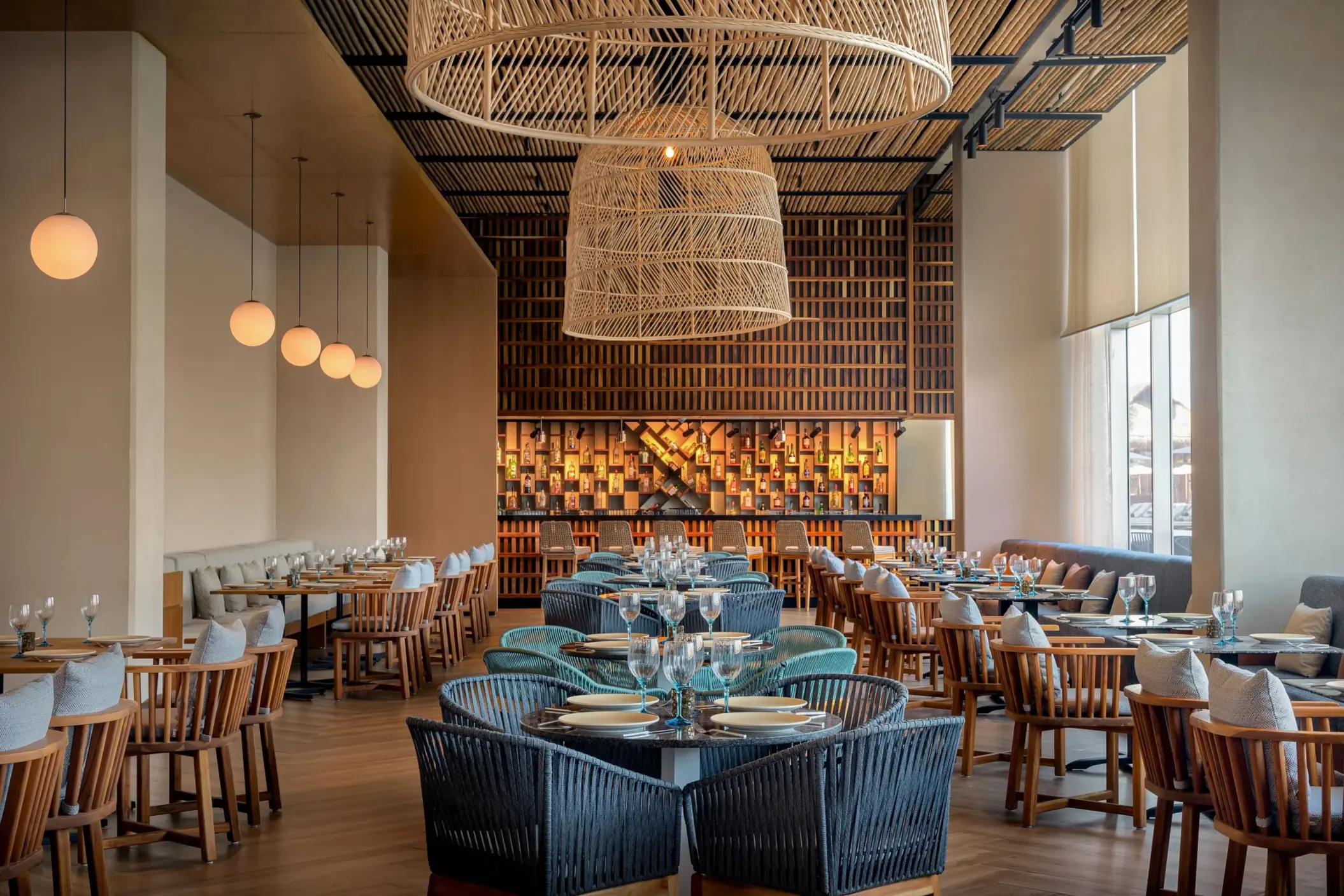 Warm Mediterranean-style restaurant with woven lights, wooden seating, and a cozy, modern aesthetic.
