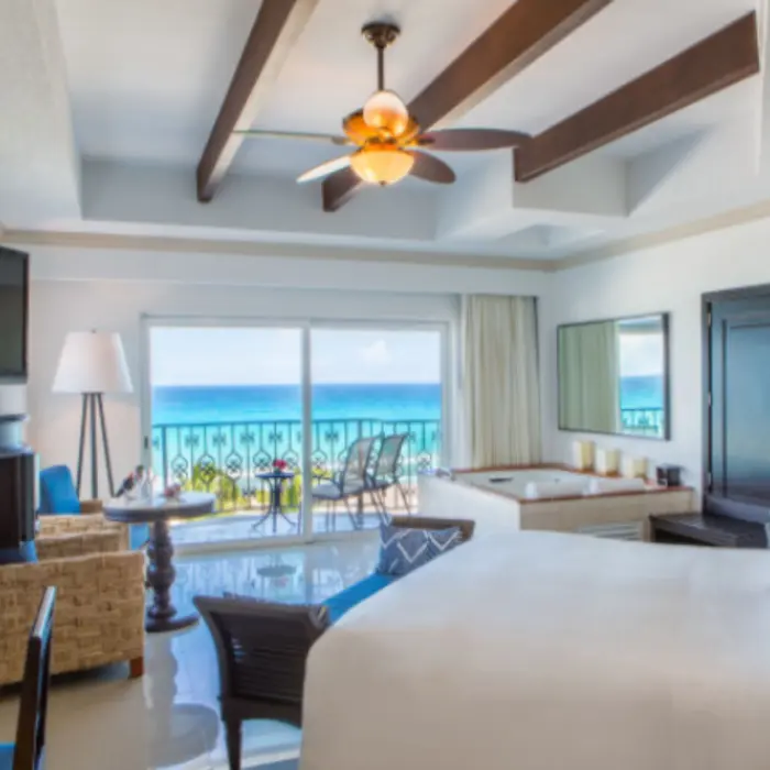 Spacious suite with ocean view, ceiling fan, hot tub, and balcony access through sliding doors.