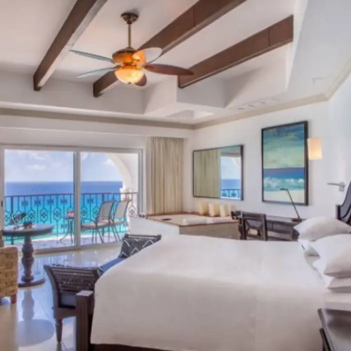 King suite with exposed beams, hot tub, and oceanfront terrace with seating.