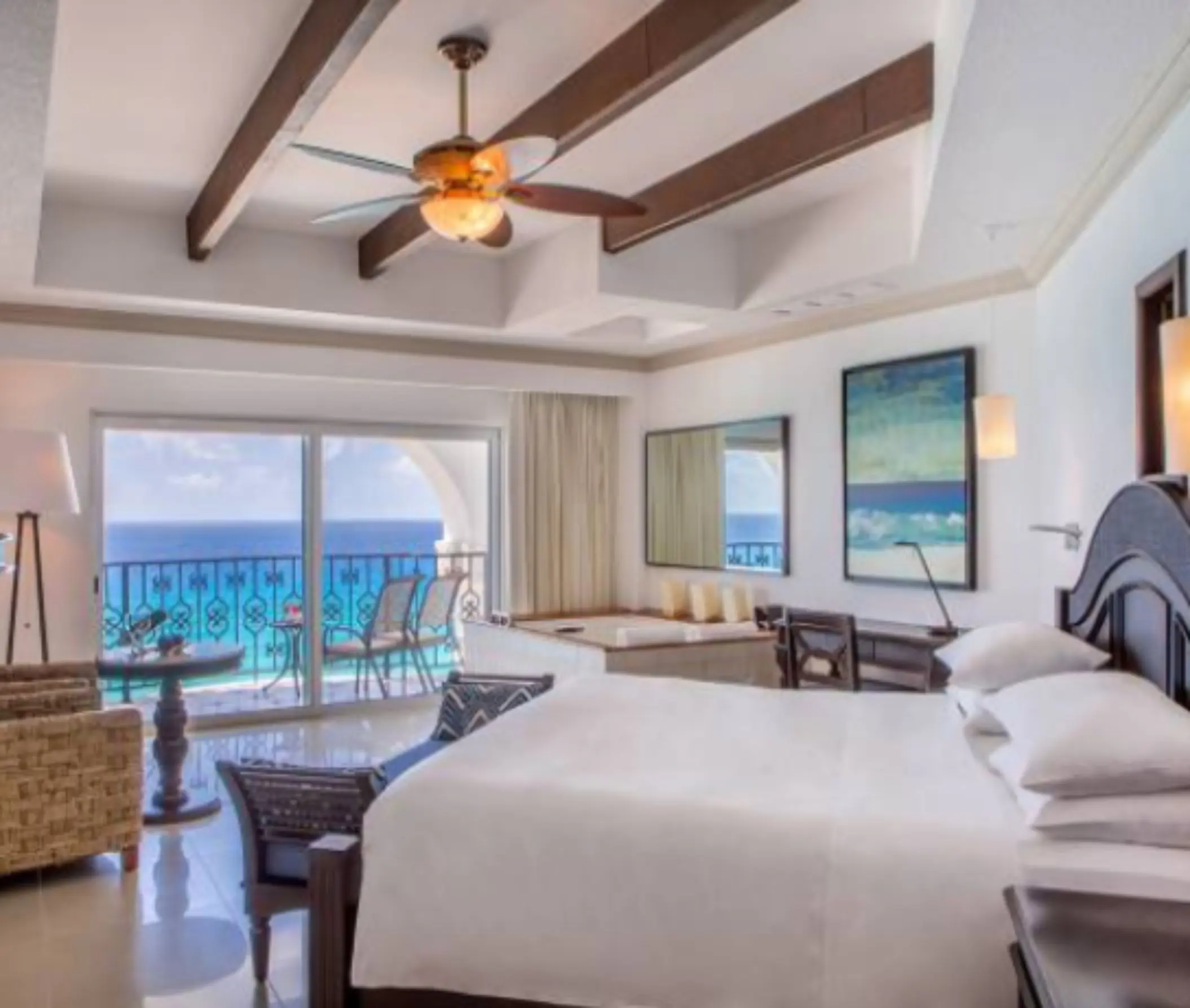 King suite with exposed beams, hot tub, and oceanfront terrace with seating.