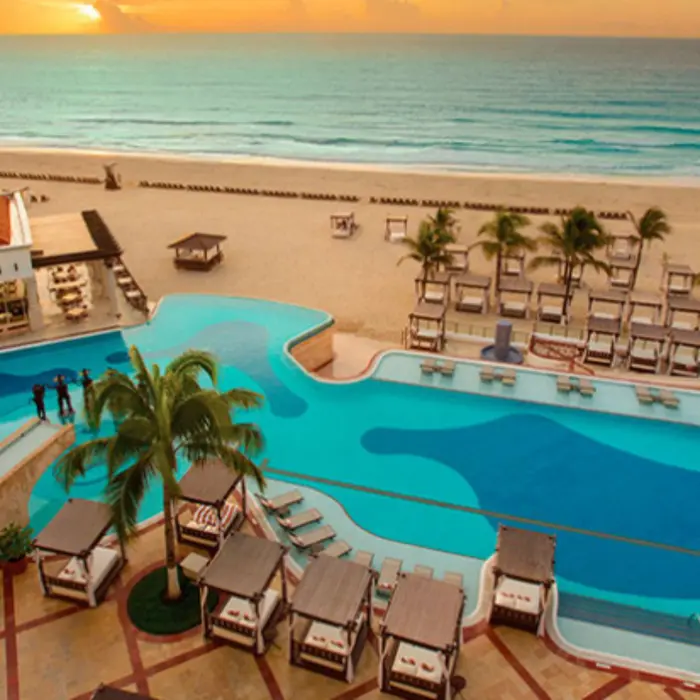 Infinity pool overlooking the beach with daybeds and ocean views during a golden Caribbean sunset.