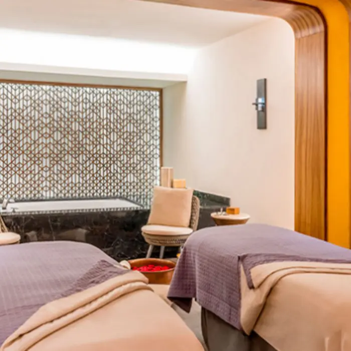 Couples massage room with elegant wood accents and a tranquil setting for a soothing spa session.