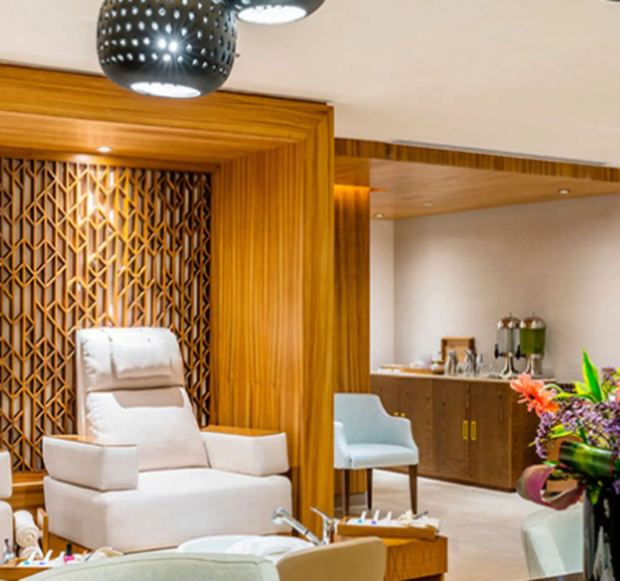 Spa salon area with plush pedicure chairs, wood paneling, and refreshments for a full pampering session.