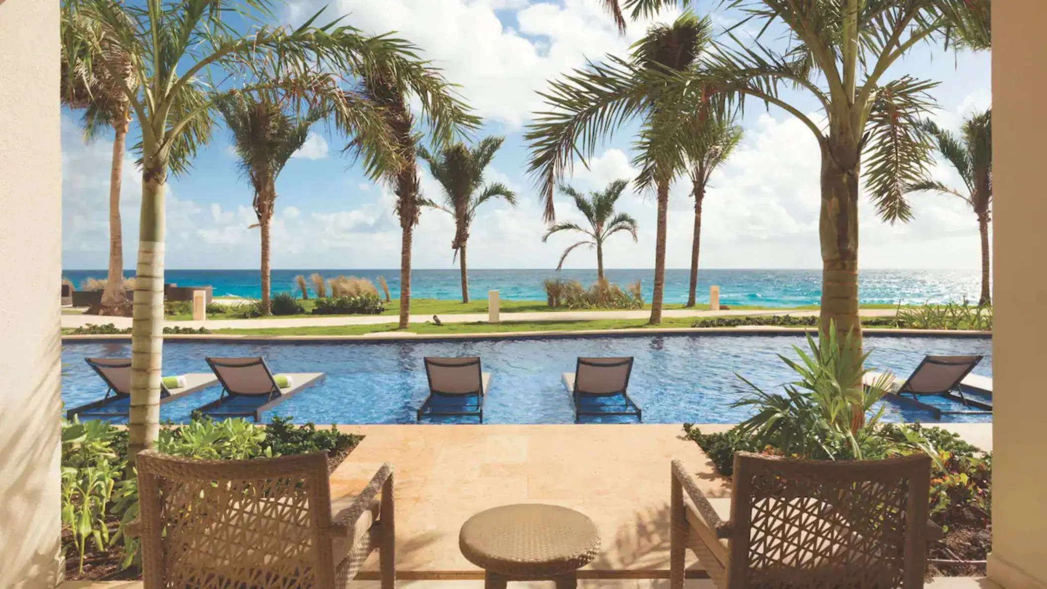 furnished balcony with view of the pool and ocean at the swim up king suite at Hyatt Ziva Cancun