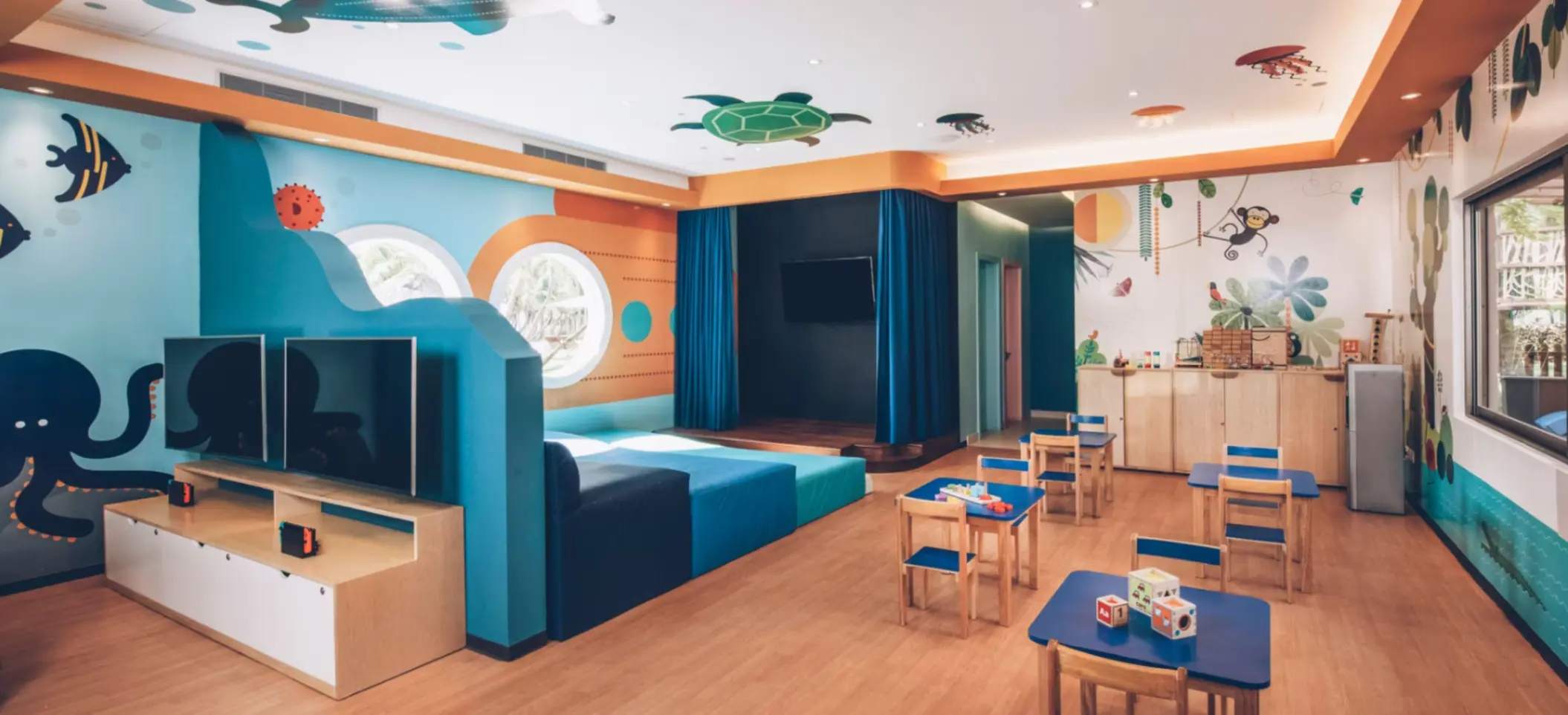 Sleek, modern kids club with ceiling feature, warm lighting, and minimalist furniture in a luxury resort setting.