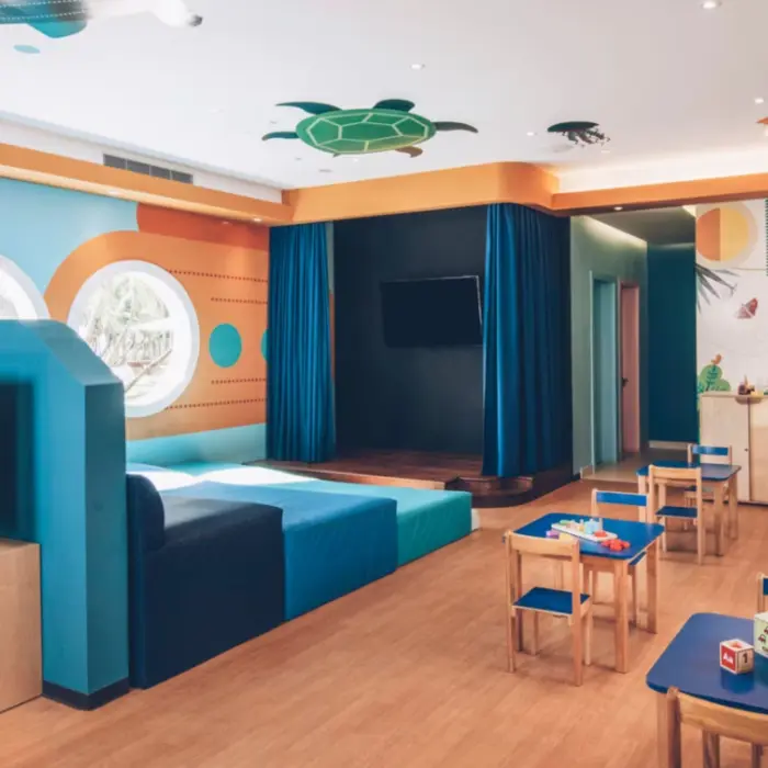 Sleek, modern kids club with ceiling feature, warm lighting, and minimalist furniture in a luxury resort setting.