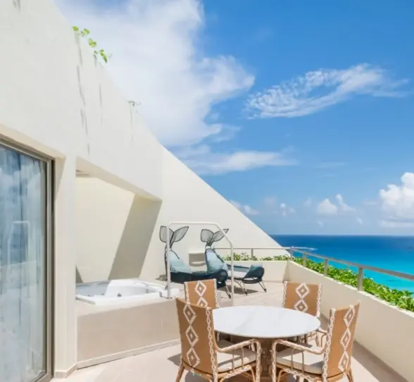 Spacious terrace with hot tub, lounge chairs, dining set, and breathtaking view of turquoise Caribbean waters.