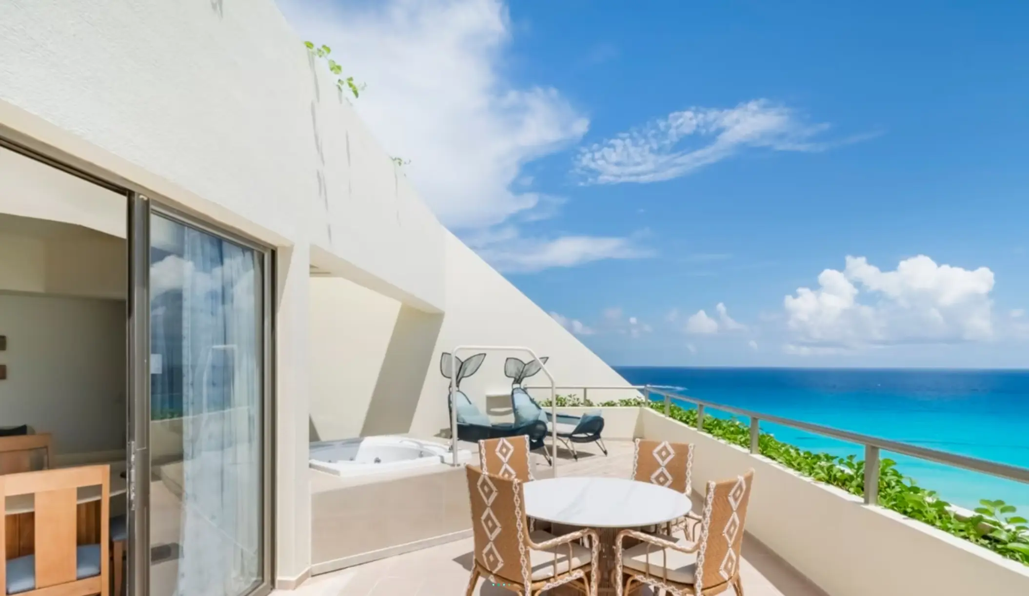 Spacious terrace with hot tub, lounge chairs, dining set, and breathtaking view of turquoise Caribbean waters.
