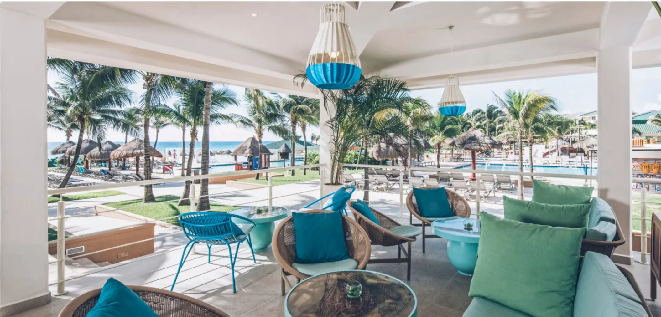 Serene beachfront with hammocks tied between palm trees, soft sand, and turquoise water stretching into the horizon.