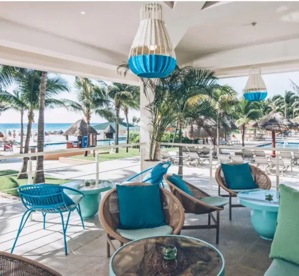 Serene beachfront with hammocks tied between palm trees, soft sand, and turquoise water stretching into the horizon.
