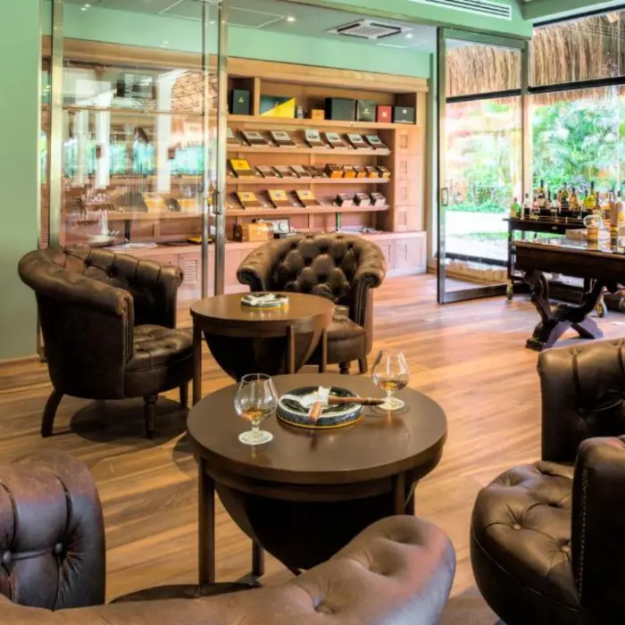 A comfortable cigar lounge with leather chairs and cigars displayed on a back wall.