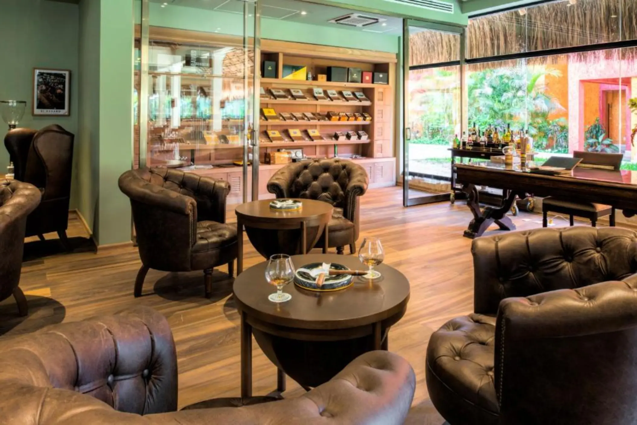 A comfortable cigar lounge with leather chairs and cigars displayed on a back wall.