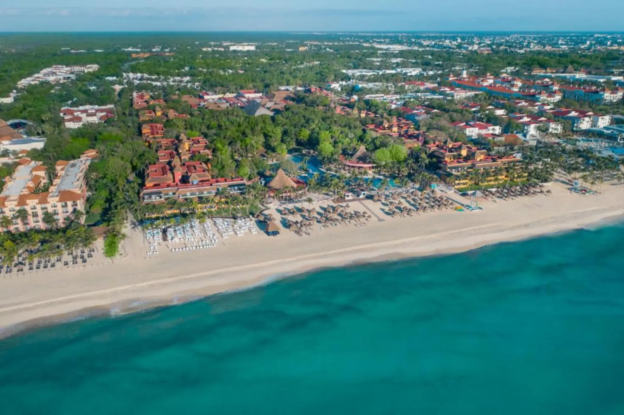 A wide aerial shot of the resort, showing the building roofs and the resort's beachfront.