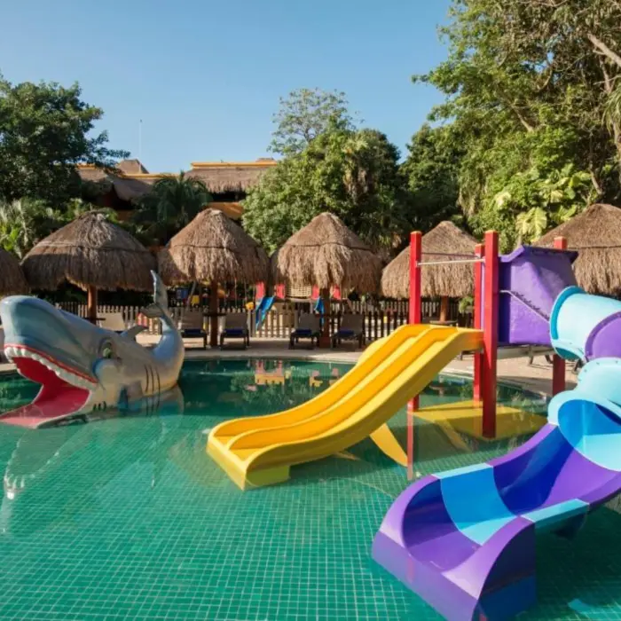 A kids' pool with a large shark sculpture and two colorful waterslides.