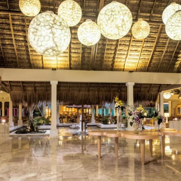 The resort's lobby, with marble floors, a high thatched roof, and hanging globular lights.