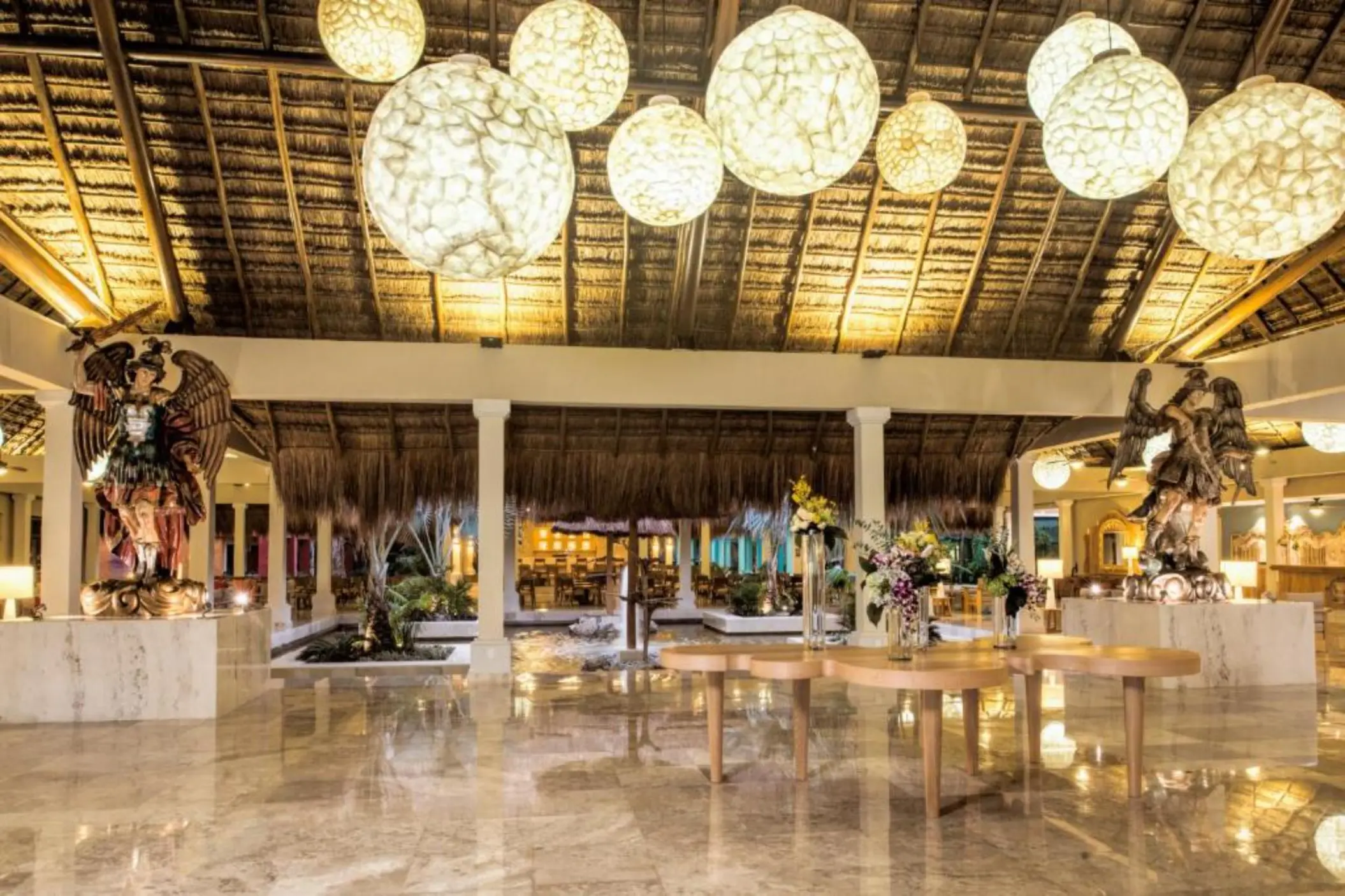 The resort's lobby, with marble floors, a high thatched roof, and hanging globular lights.