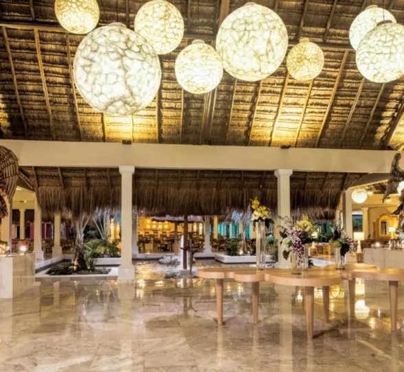 The resort's lobby, with marble floors, a high thatched roof, and hanging globular lights.