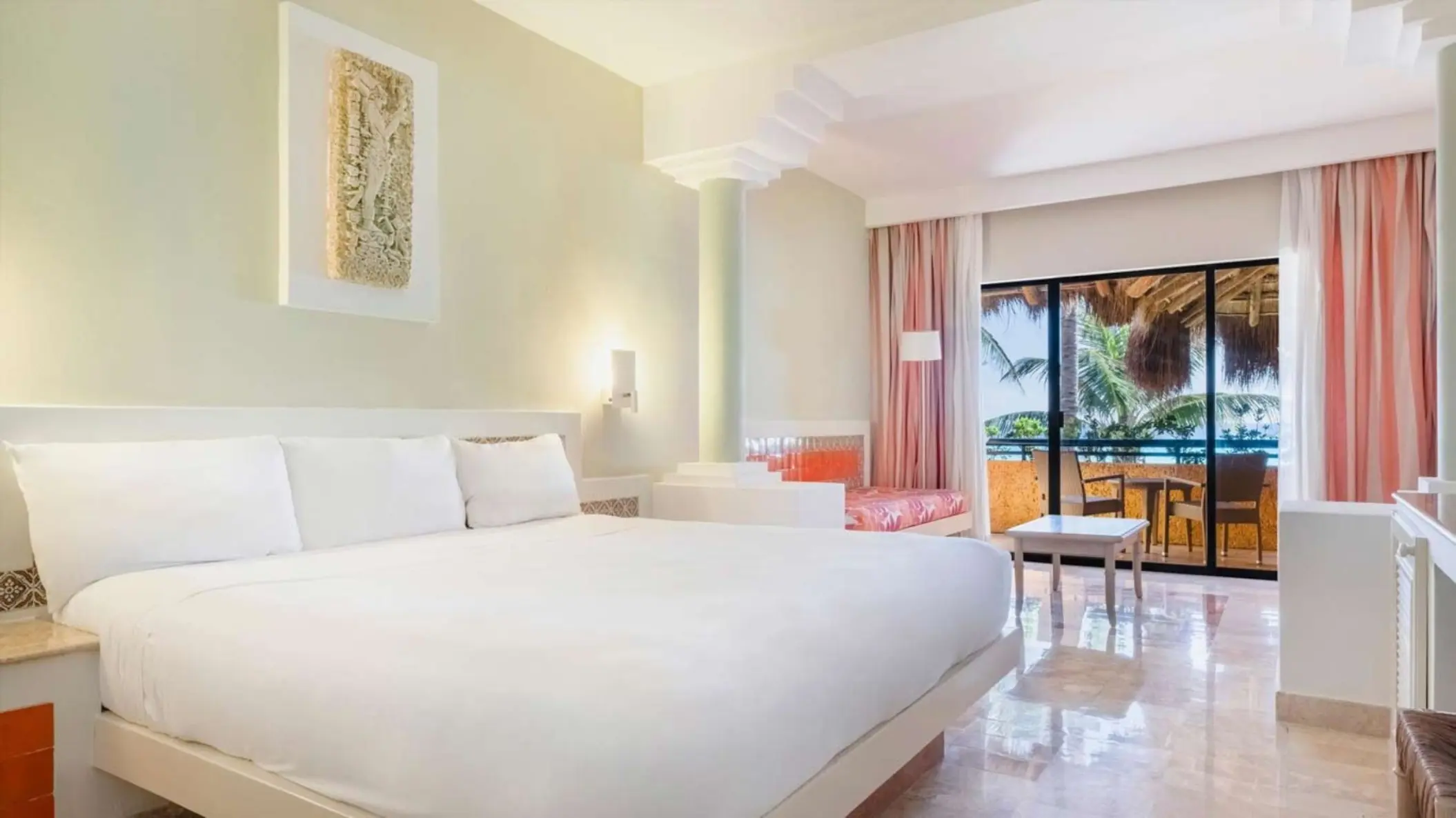 A hotel suite with a large bed and a balcony that overlooks the tropical gardens.