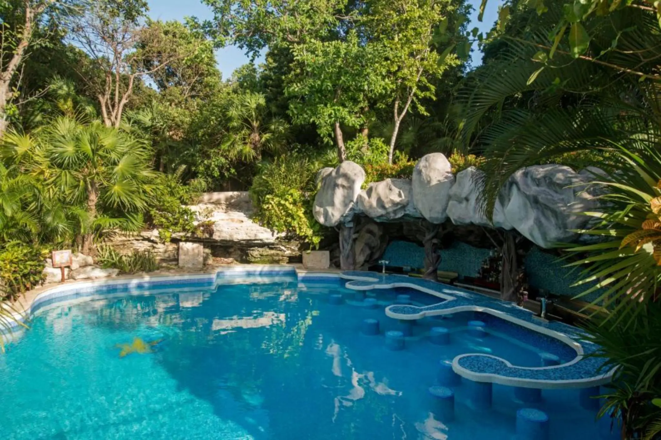 A pool with a swim-up bar and barstools built directly into the water.