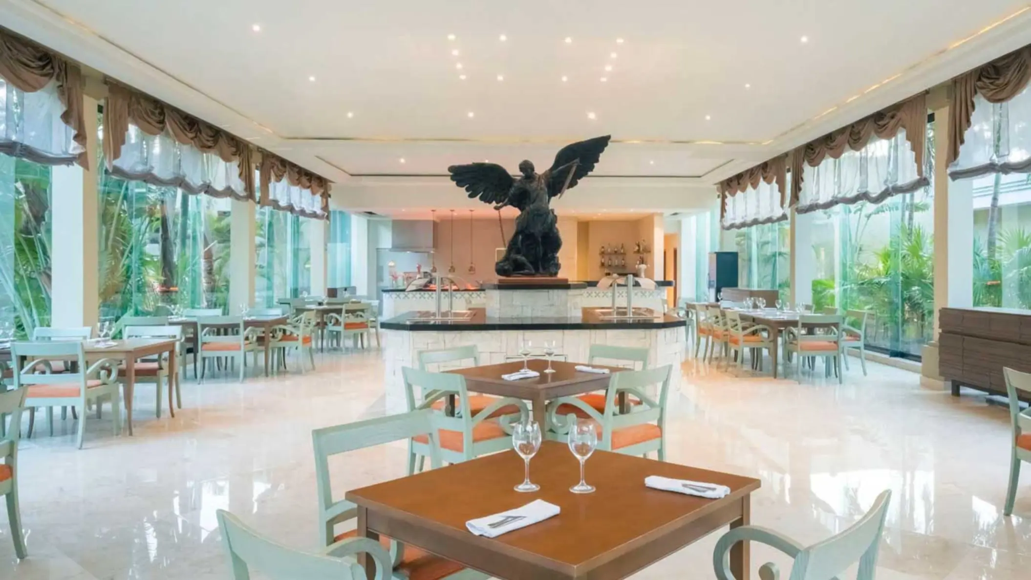 A bright, spacious restaurant with a large statue in the center, surrounded by dining tables.