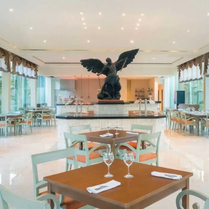 A bright, spacious restaurant with a large statue in the center, surrounded by dining tables.