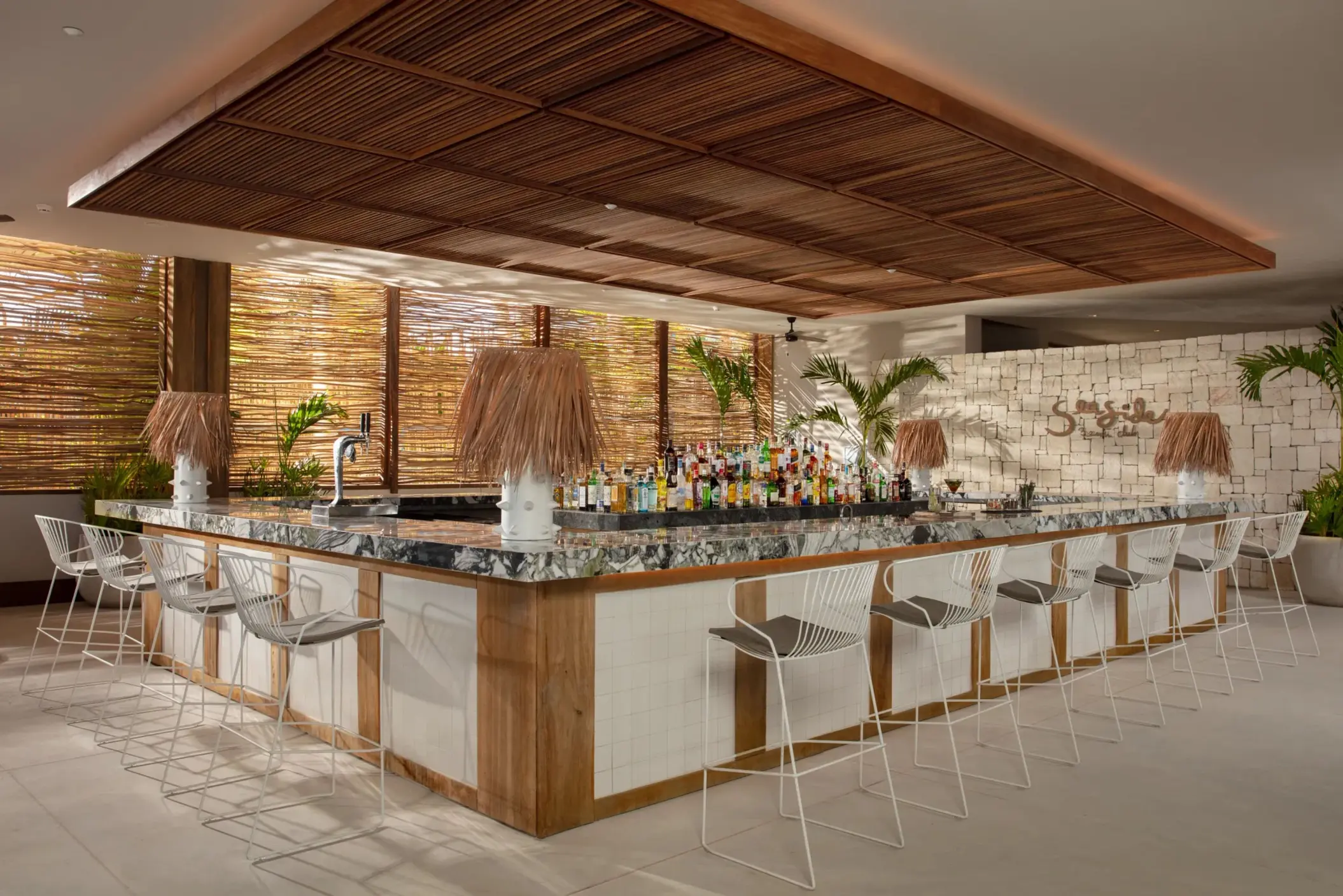 Seaside Beach Club bar with tropical vibes, marble counter, and rattan accents.
