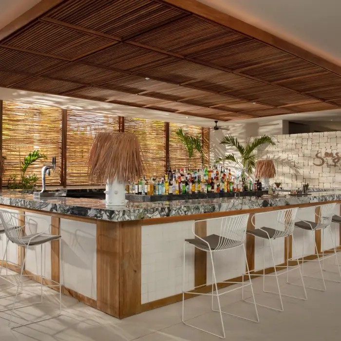 Seaside Beach Club bar with tropical vibes, marble counter, and rattan accents.