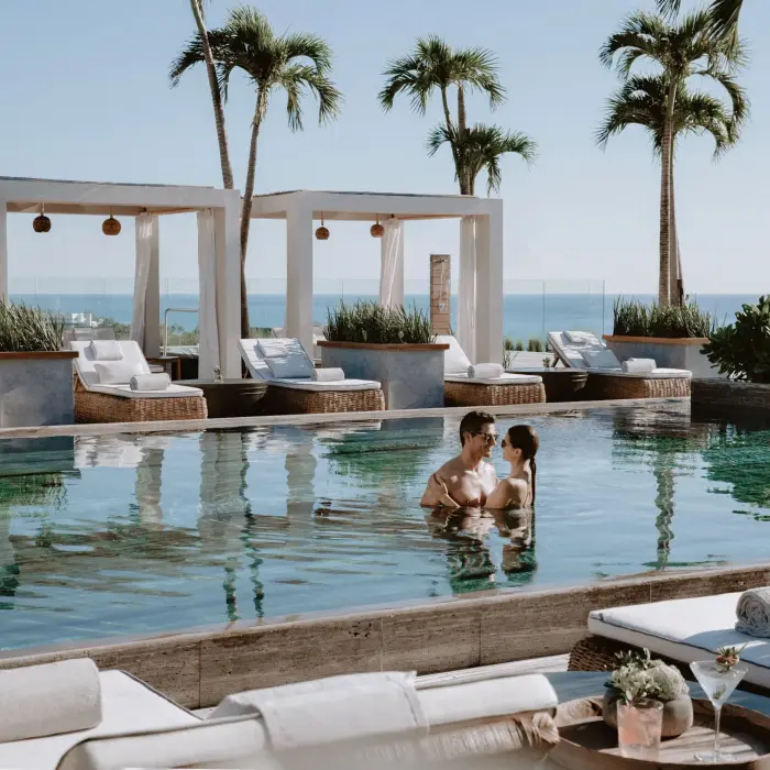 Couple enjoying rooftop pool at Secrets Impressions Moxché with ocean view cabanas.