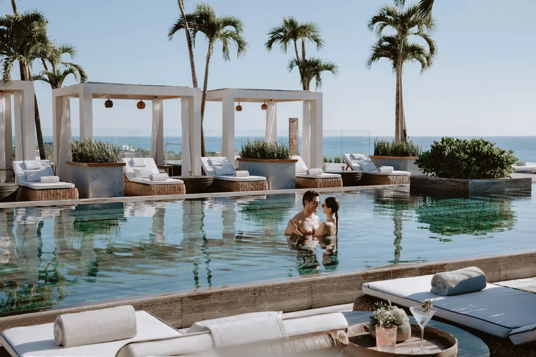 Couple enjoying rooftop pool at Secrets Impressions Moxché with ocean view cabanas.