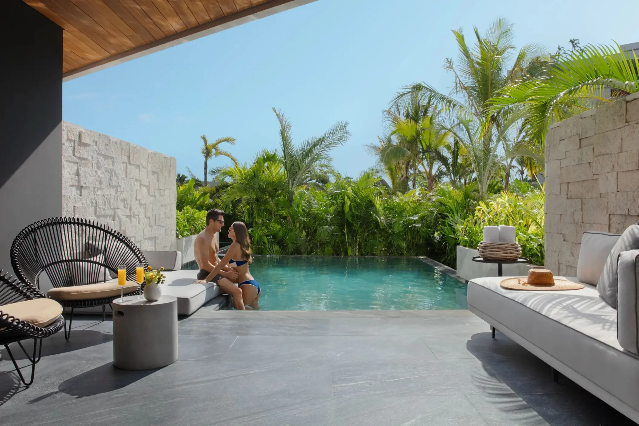 Private swim-out suite with tropical plants and modern outdoor seating area.