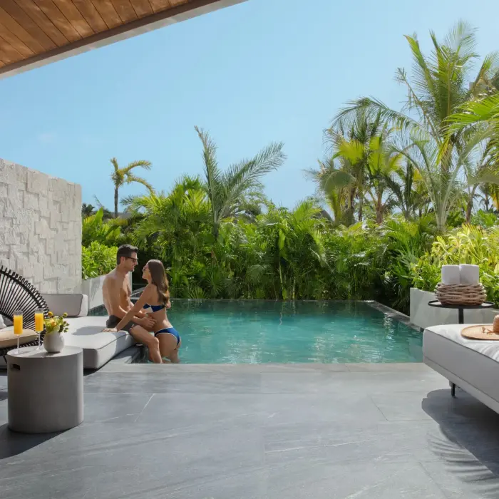 Private swim-out suite with tropical plants and modern outdoor seating area.
