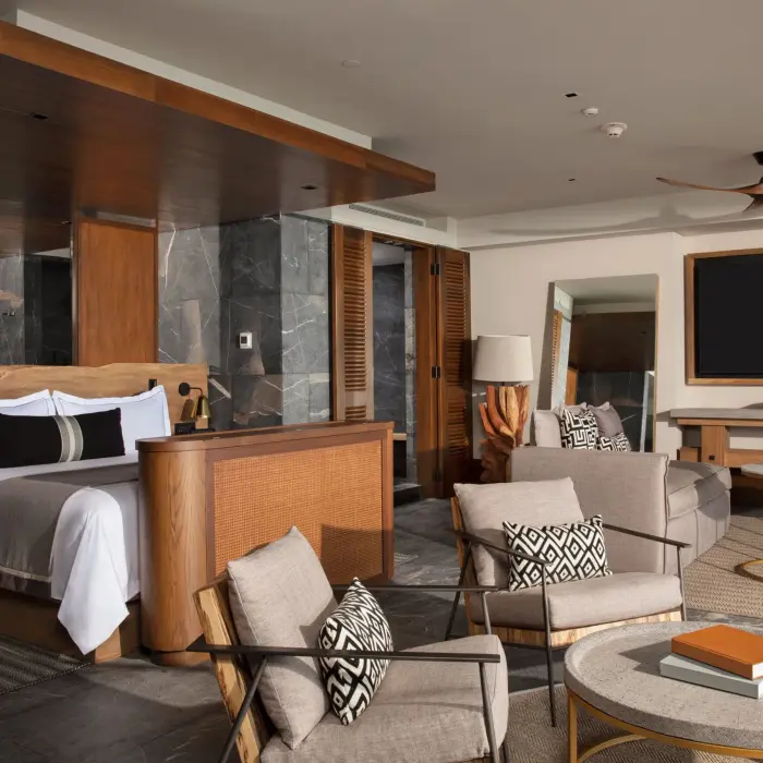 Master suite with king bed, stylish lounge area, and modern wood finishes.