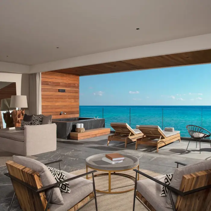 Elegant suite living room with kitchen island and open terrace ocean view.