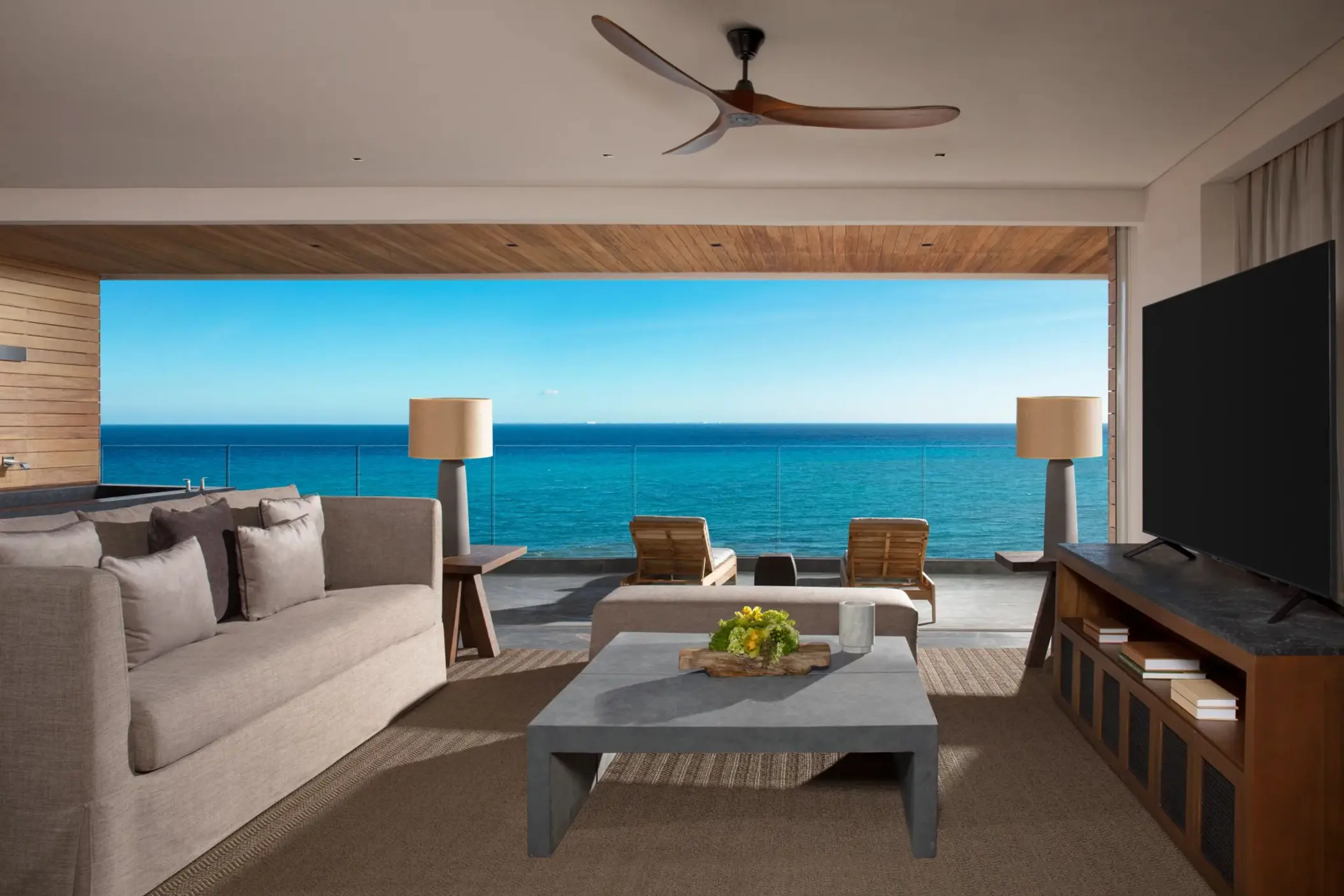 Panoramic suite with sofa, modern décor and floor-to-ceiling oceanfront view.