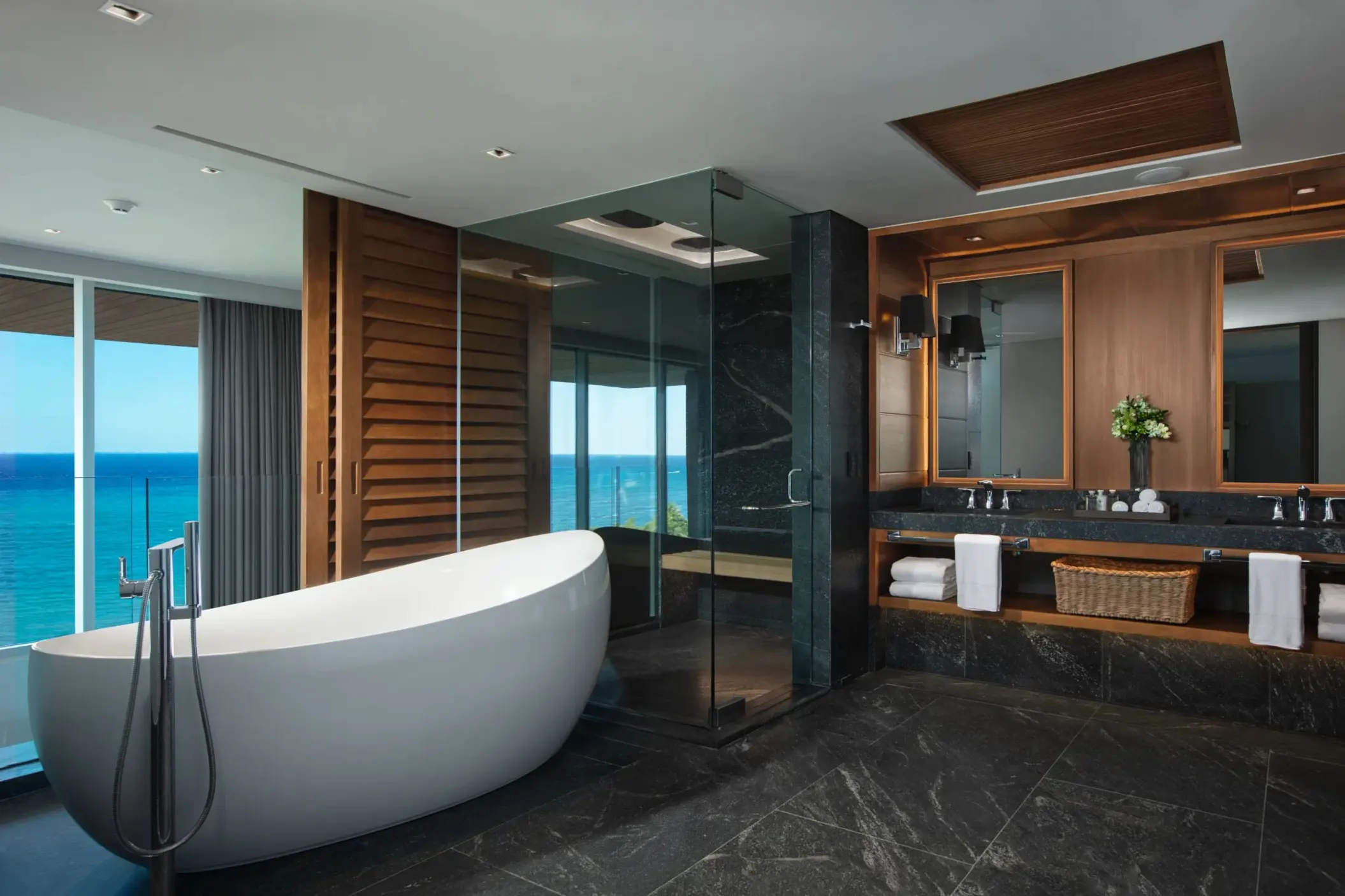 Penthouse bathroom with round tub, glass shower and dual vanity sinks.