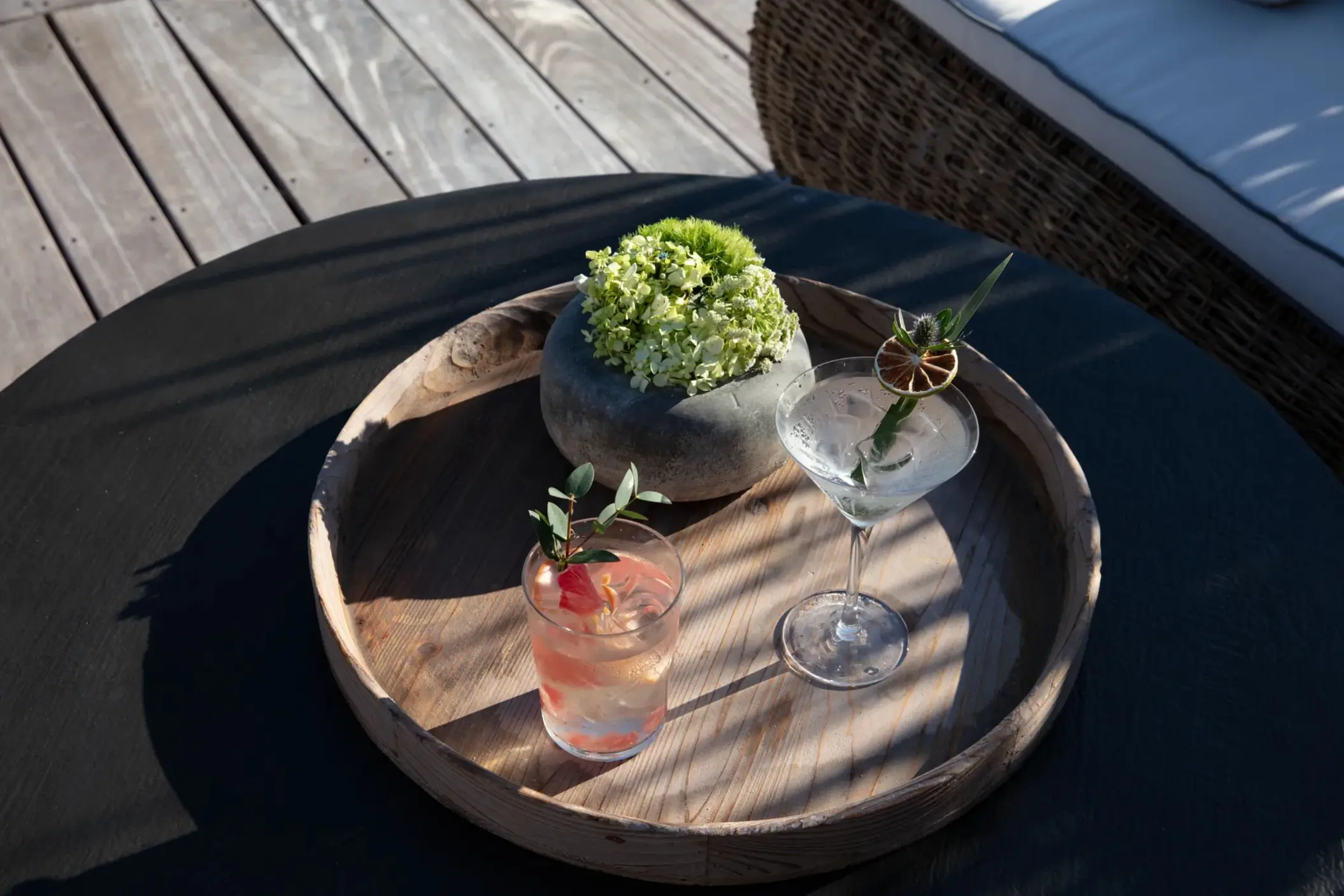 Two handcrafted cocktails served on a wooden tray by the poolside lounge.