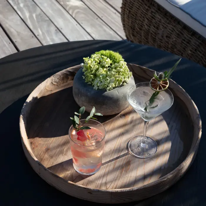 Two handcrafted cocktails served on a wooden tray by the poolside lounge.