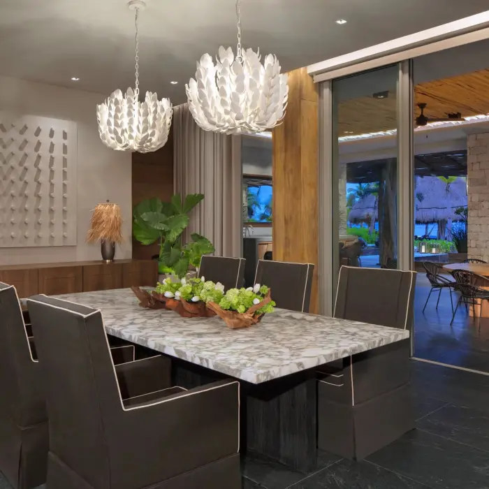 Elegant private dining room with modern chandeliers, marble table and outdoor access.