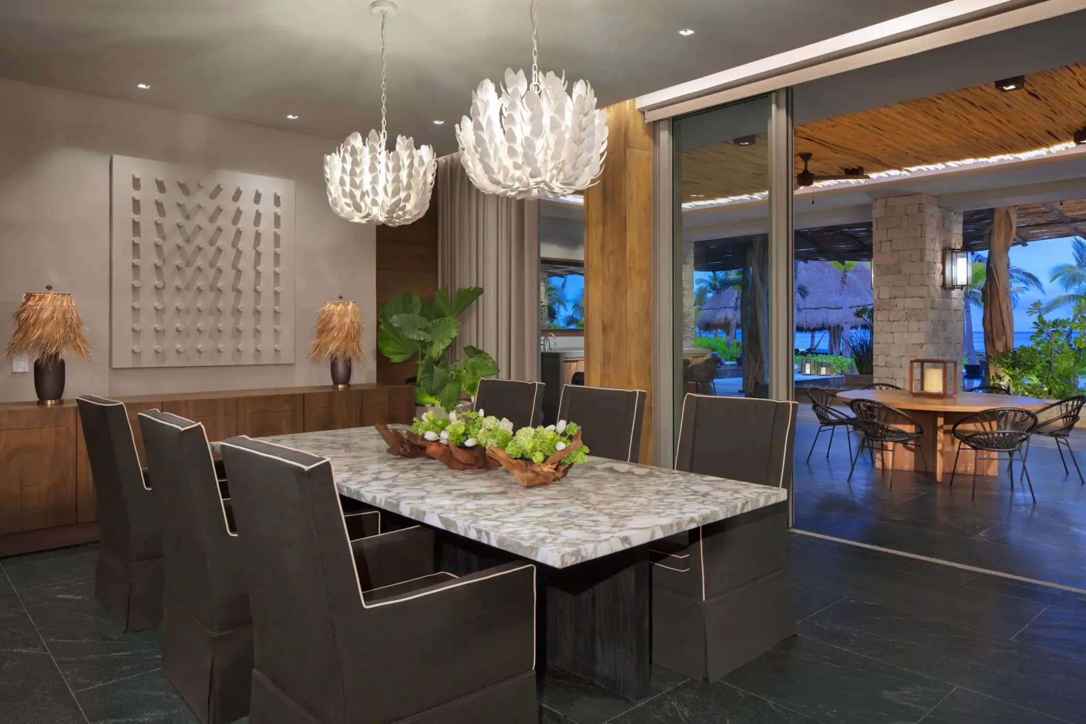 Elegant private dining room with modern chandeliers, marble table and outdoor access.