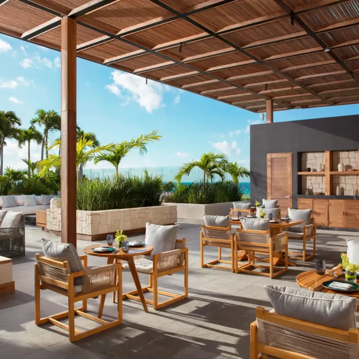 Upscale open-air restaurant with ocean views and modern wooden furnishings at Secrets Impression Moxché.