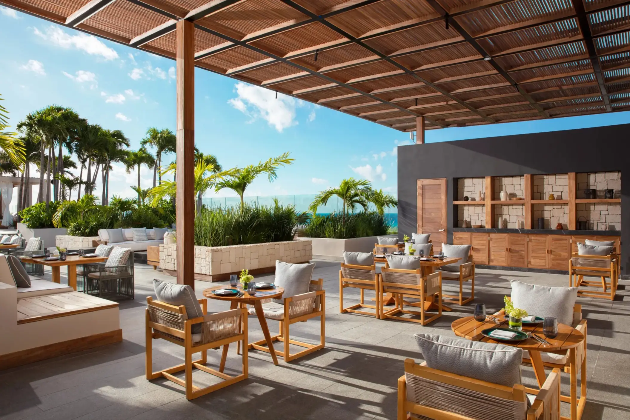 Upscale open-air restaurant with ocean views and modern wooden furnishings at Secrets Impression Moxché.