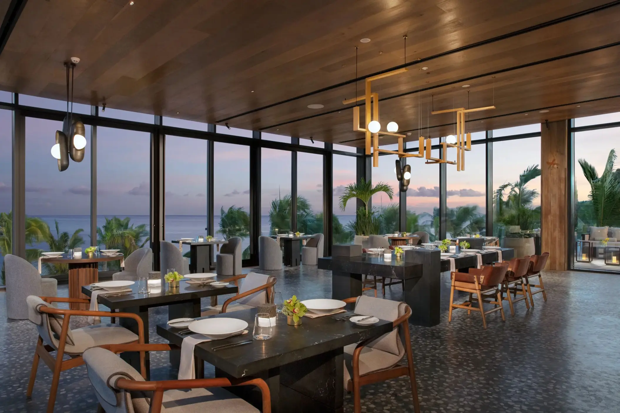 Elegant dining room at Teodoro with ocean sunset views and contemporary lighting at Secrets Impression Moxché.
