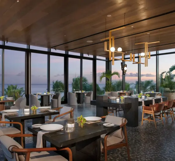 Elegant dining room at Teodoro with ocean sunset views and contemporary lighting at Secrets Impression Moxché.