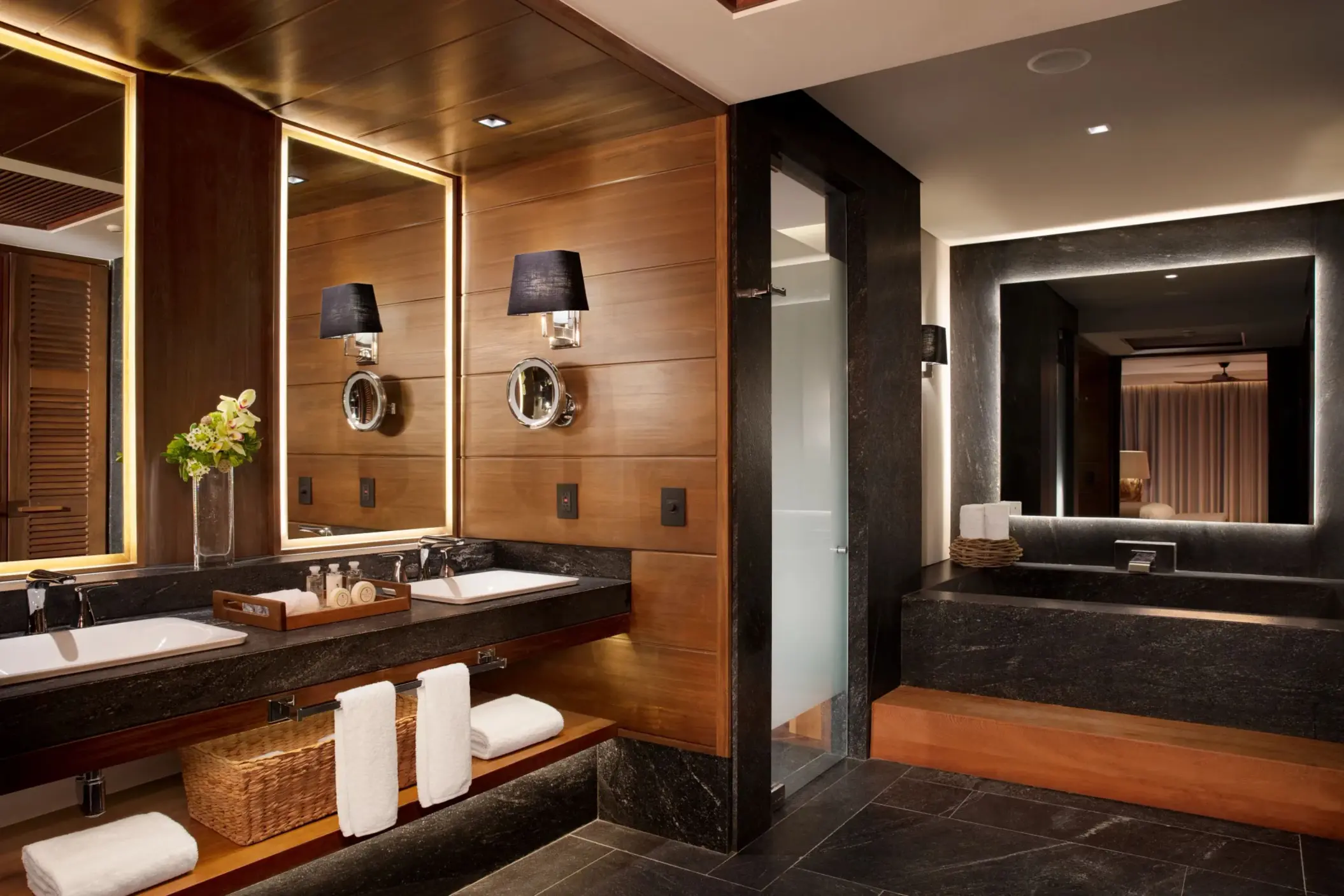 Luxurious bathroom with dual vanities, soaking tub, and dark stone finishes in the Signature Suite.